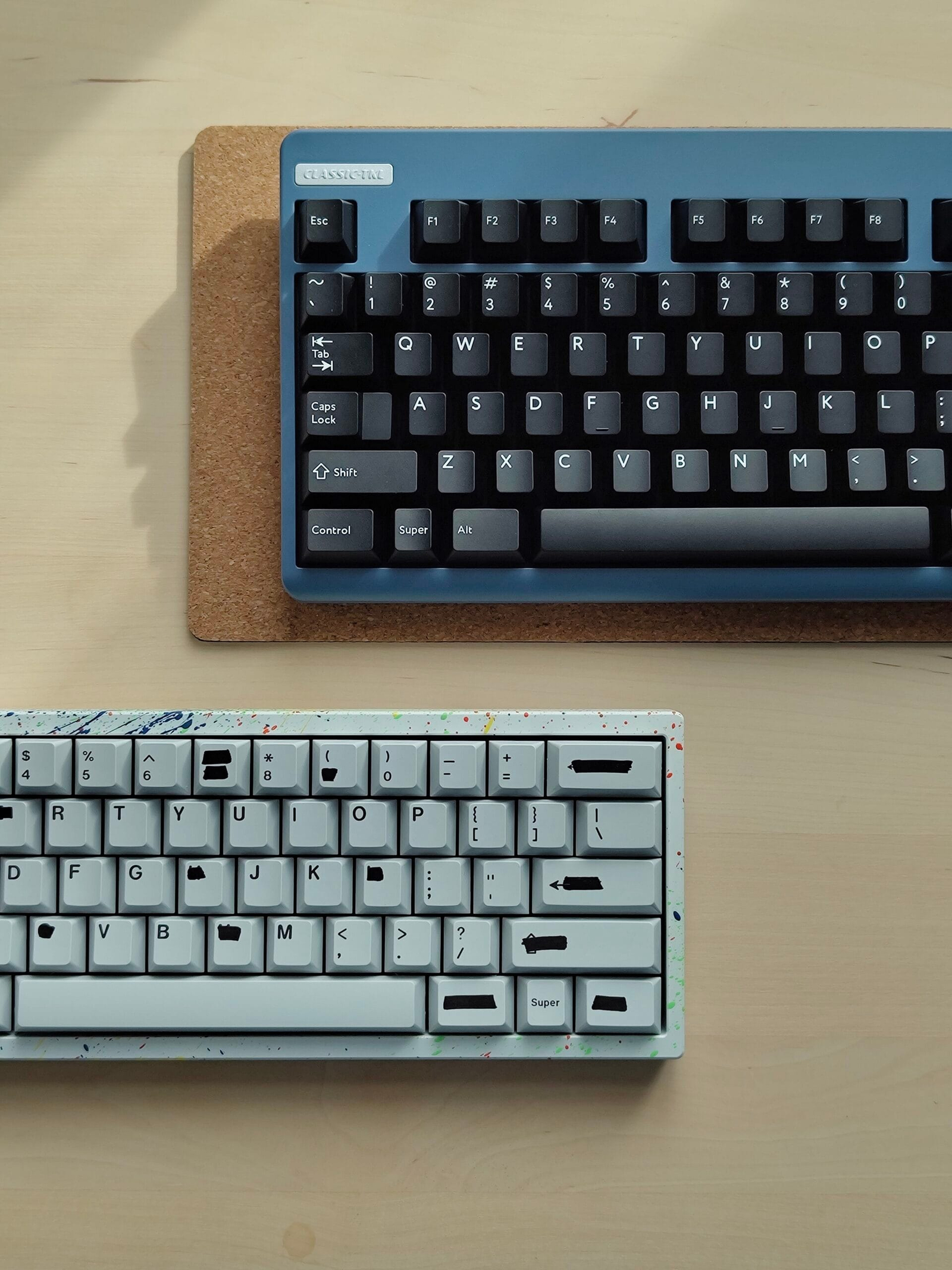 Blue and grey keyboards on a cork mat