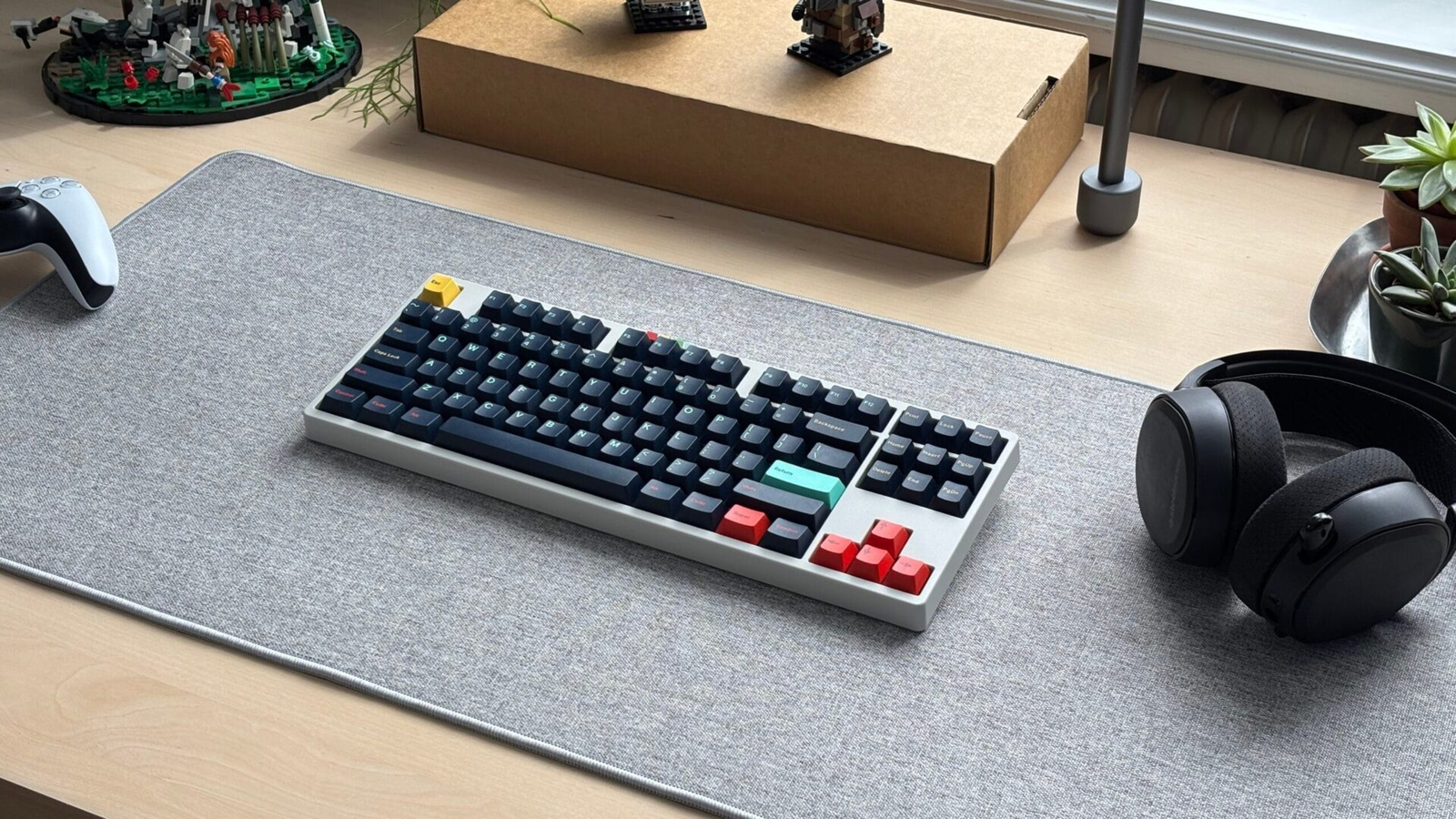 Custom mechanical keyboard on a desk with a PlayStation controller and headphones