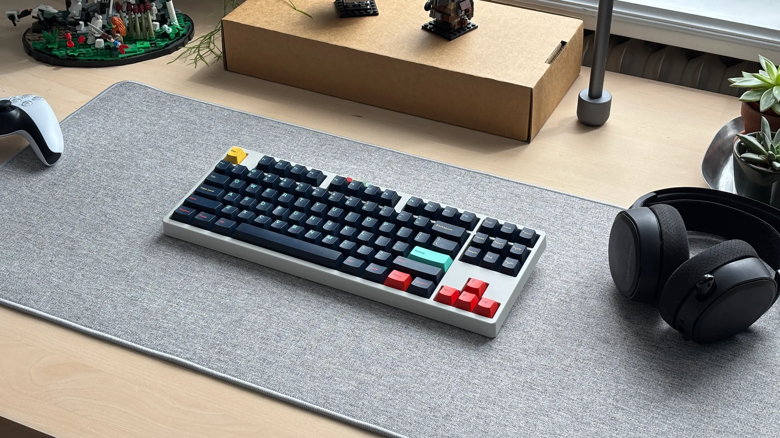 Custom mechanical keyboard on a desk with a PlayStation controller and headphones